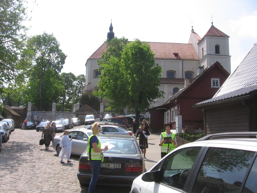 UAB „Trakų paslaugos“ darbuotojos aiškinasi, kurie vairuotojai nesumokėjo už automobilių pastatymą aikštėje prie Trakų bažnyčios